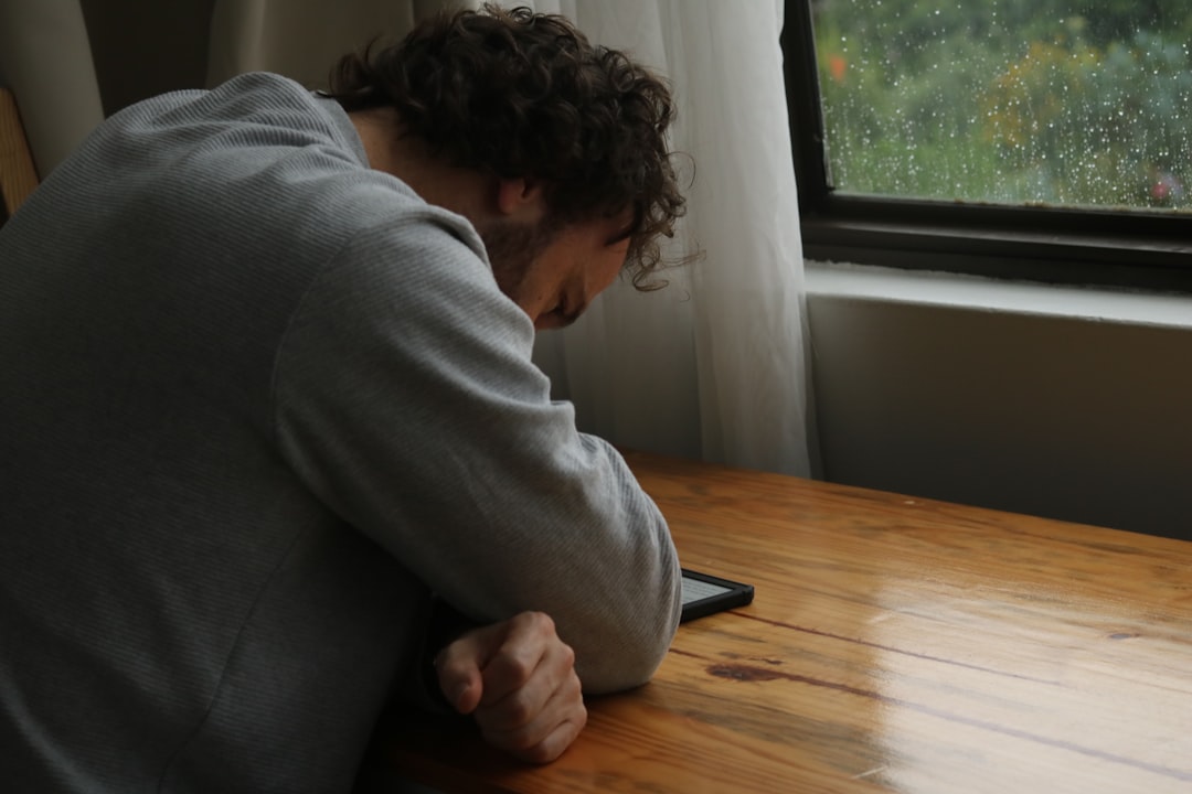 A homeowner looks stressed while sitting at a table with a calculator and paperwork, illustrating the financial anxiety of pricing a home incorrectly.