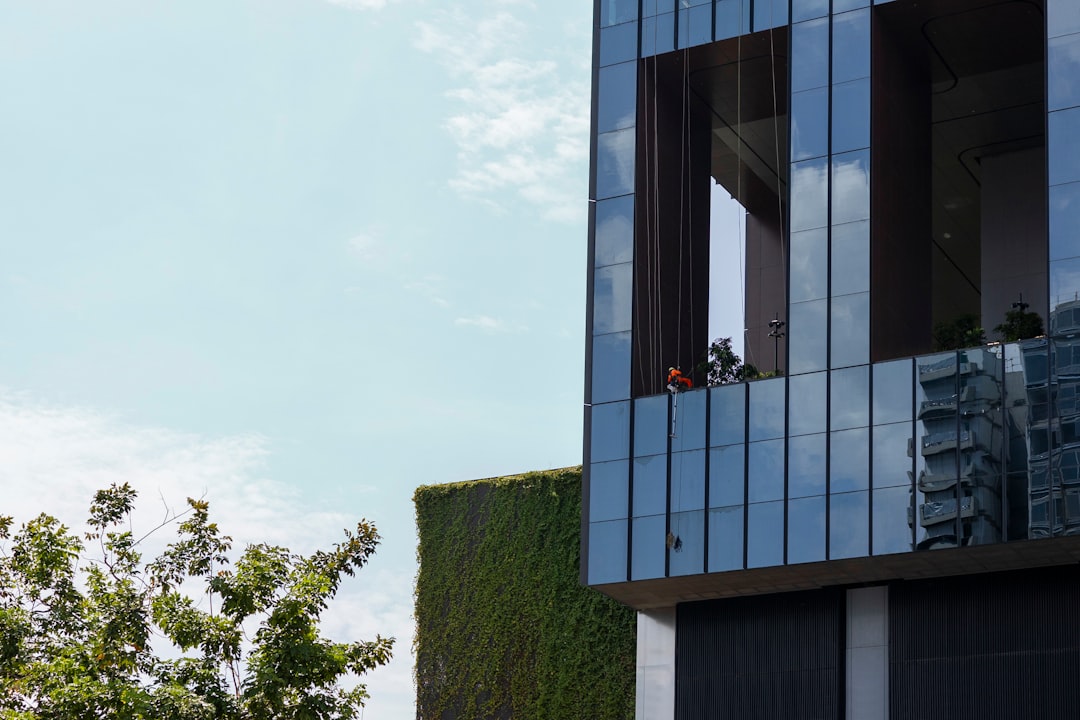 A person stands outside a modern home, holding a tablet and thoughtfully analyzing the property's exterior, representing a comparative market analysis.