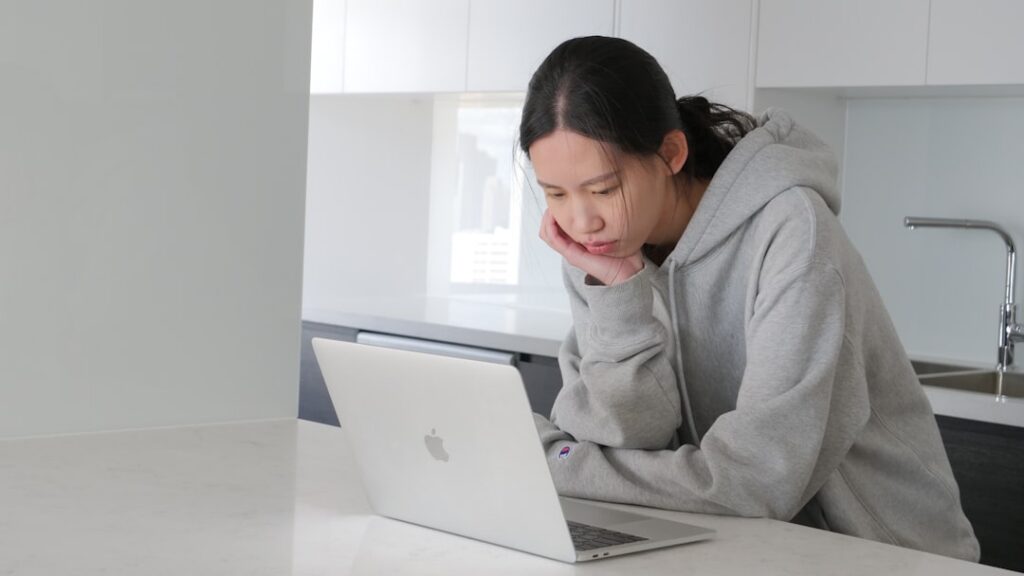 Person with a concerned expression sits at a bright, modern desk reviewing official-looking papers, symbolizing the stress...