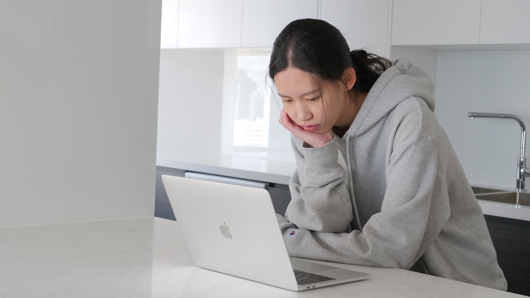 Person with a concerned expression sits at a bright, modern desk reviewing official-looking papers, symbolizing the stress...