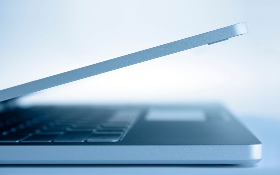 A sleek laptop and notebook on a clean, professional desk with a window view, symbolizing a modern, data-driven approach to real estate.