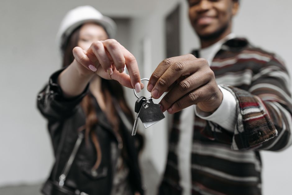 A homeowner's hand holding a set of house keys in a bright, minimalist setting, symbolizing the successful sale and financial savings.