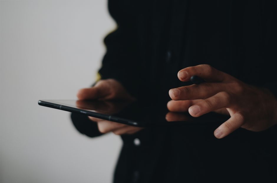 A person's hands holding a tablet displaying a real estate application with property listings, illustrating the modern, tech-forward approach to buying a home.