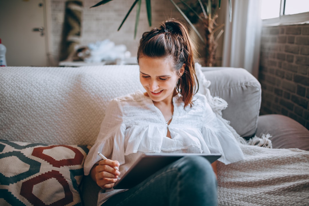 Savvy homeowner relaxes in their bright, modern living room, using a digital tablet to manage their home selling process e...