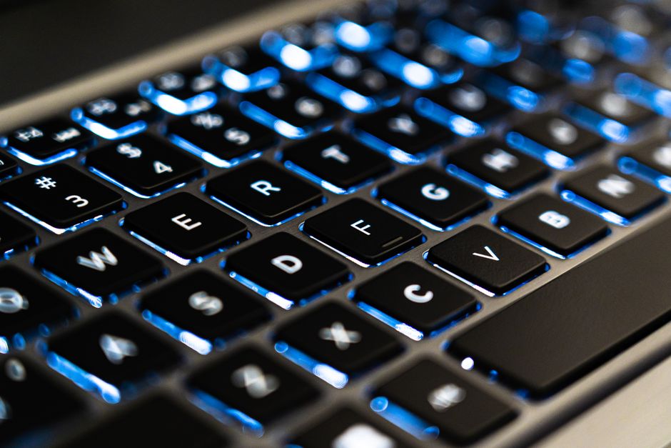A set of modern house keys rests on the keyboard of a sleek laptop, representing the intersection of real estate and digital technology.