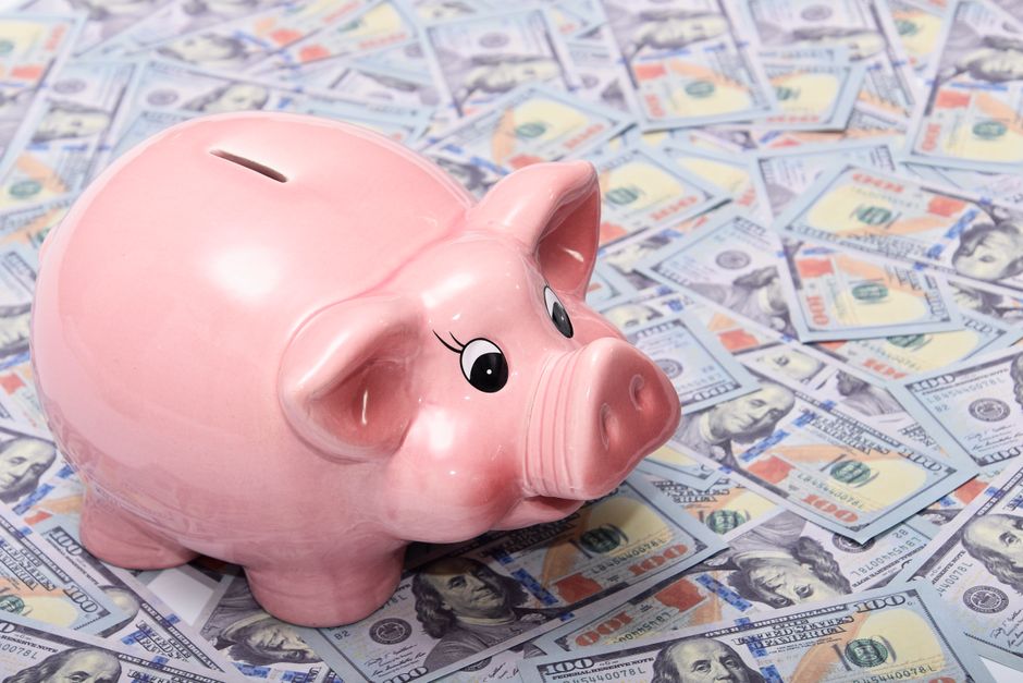 A white piggy bank sits on a table inside a bright, modern home, symbolizing the owner's hard-earned home equity and savings.