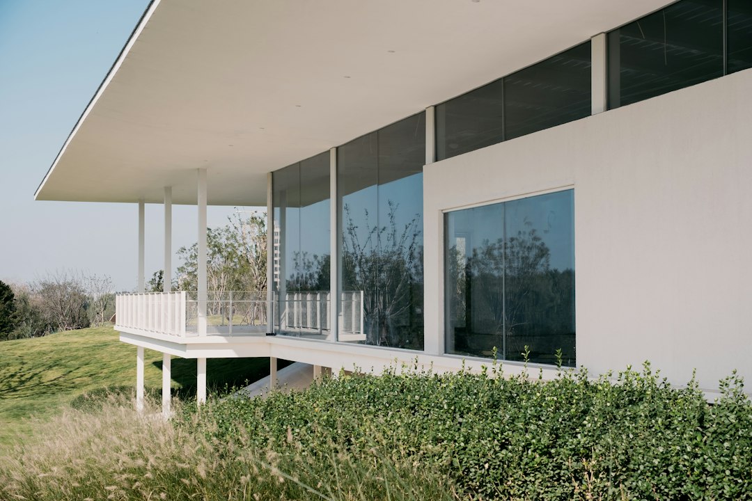 The clean, minimal exterior of a modern home with large, clear windows on a bright day, representing a fresh and transparent approach to real estate.