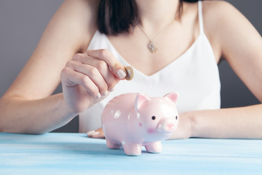A minimalist, modern piggy bank shaped like a house sits on a clean surface with coins next to it, symbolizing saving money and maximizing equity from a home sale.
