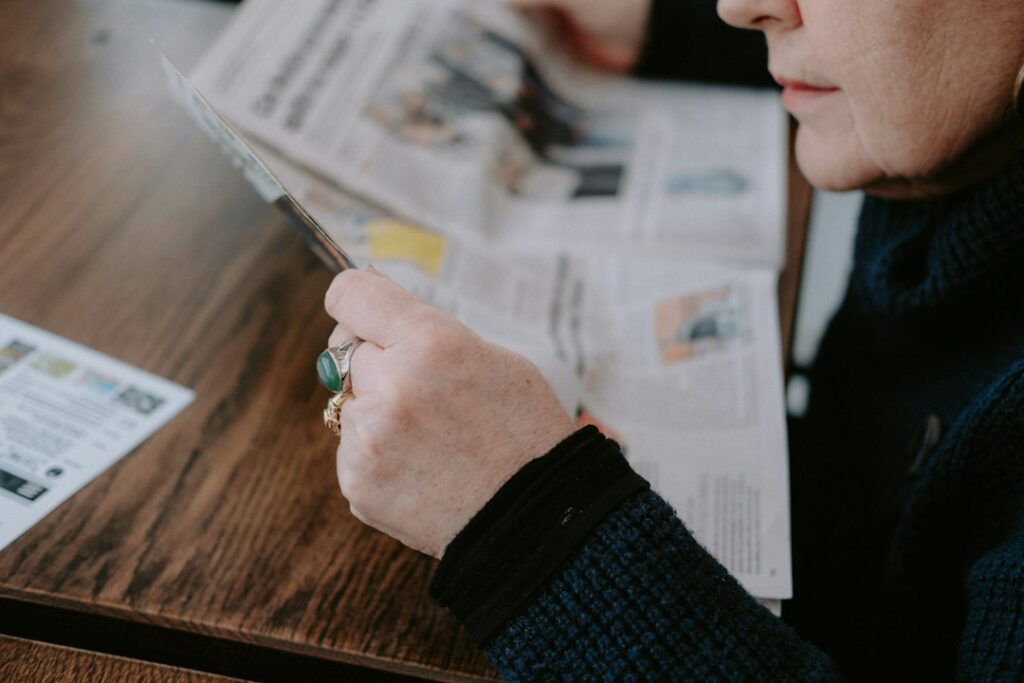 Person in a bright, professional setting using a magnifying glass to closely inspect the fine print on a contract, represe...