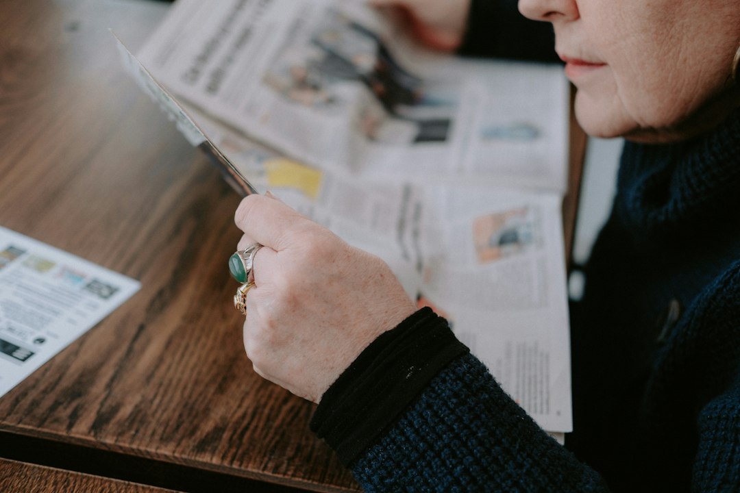 Person in a bright, professional setting using a magnifying glass to closely inspect the fine print on a contract, represe...